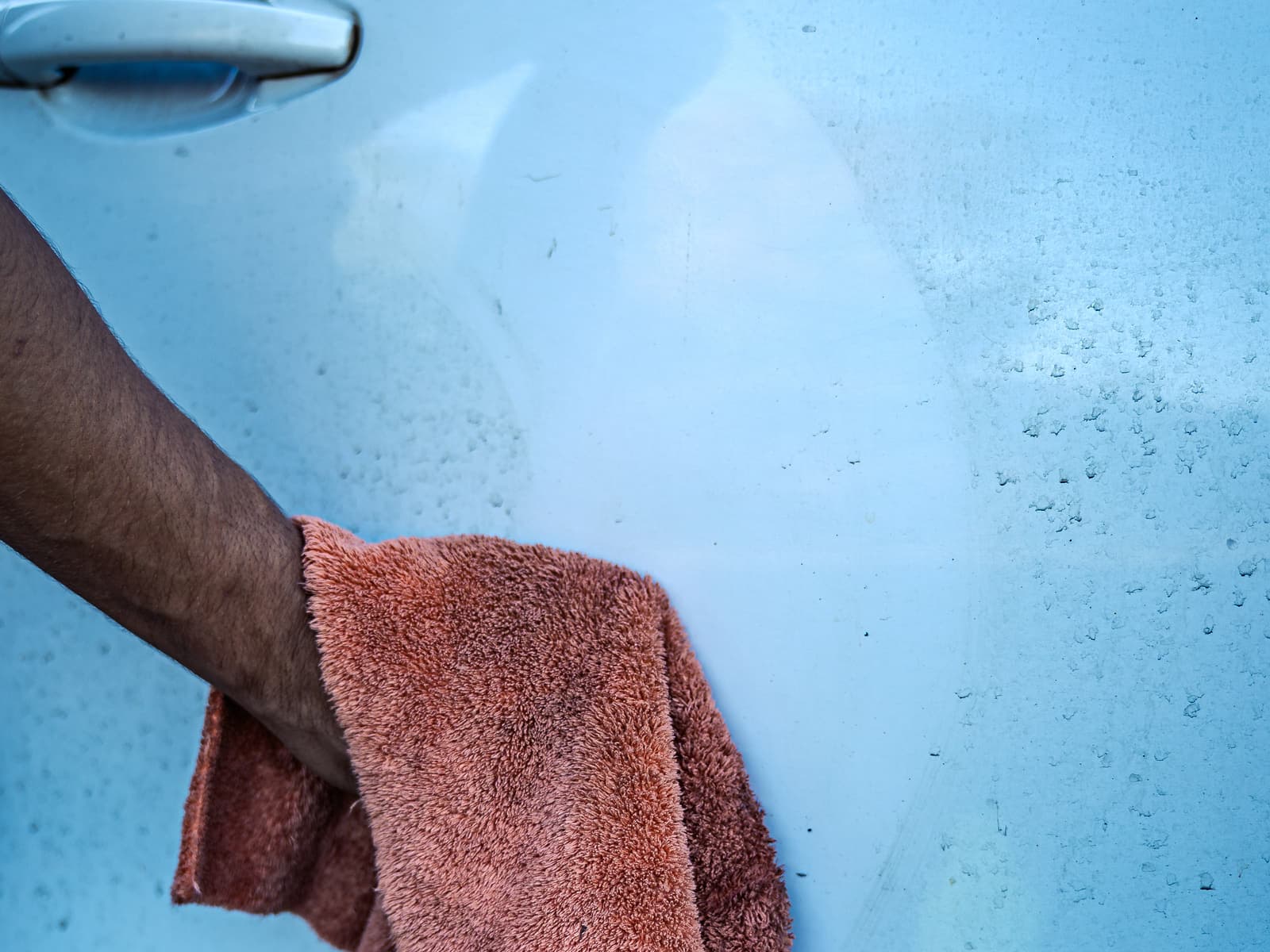 Retrait du produit à la microfibre sur une portière : la zone traitée tranche avec la poussière restante