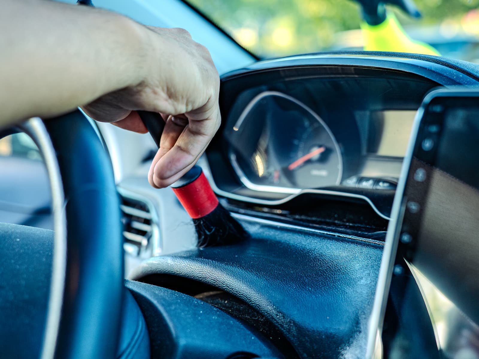 Dépoussiérage au pinceau des grilles d'aération et du tableau de bord d'une voiture